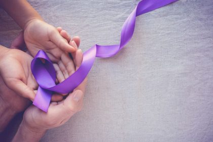 Hands holding Purple ribbons, toning copy space background, Alzheimer disease, Pancreatic cancer, Epilepsy awareness, domestic violence wareness