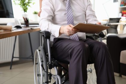 Employee man working in an office on wheelchair. Guarantee for protection labor rights workers with disabilities. Special educational institutions and workshops for people with disabilities