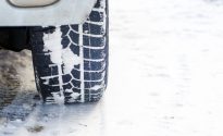 Car tires on winter road covered with snow. Vehicle on snowy alley in the morning at snowfall