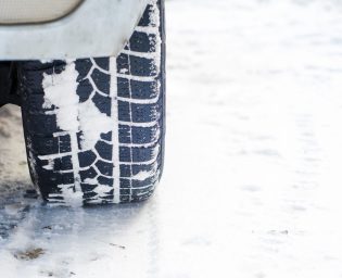Car tires on winter road covered with snow. Vehicle on snowy alley in the morning at snowfall