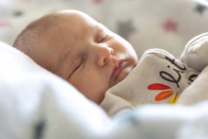 Newborn baby sleep. Girl infant sleep lies in child bed. High quality photo. Cute sleeping baby. Space for text.